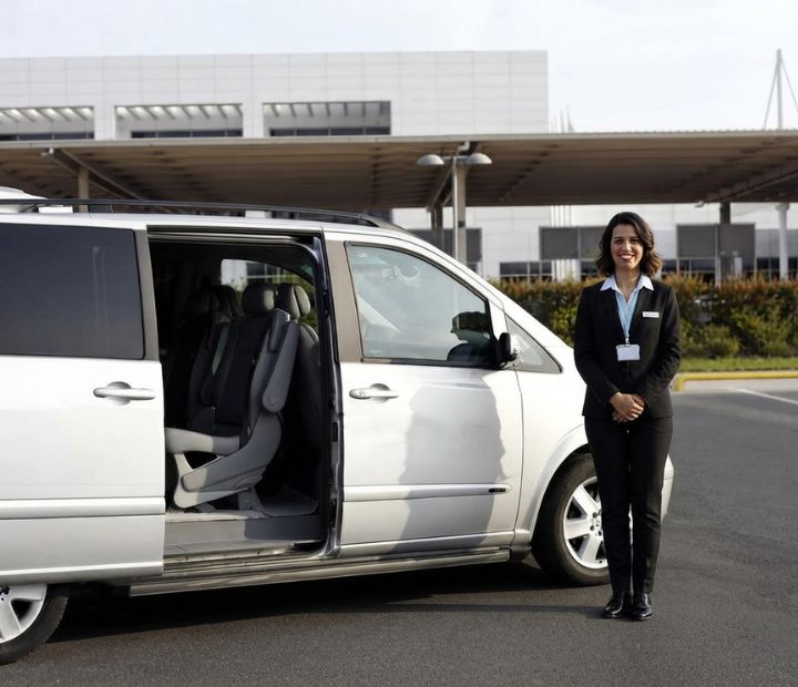 Coordinadora de logística y transporte sonriente junto a una van de traslado para pacientes a la Clínica Láser de Ojos Medellín.