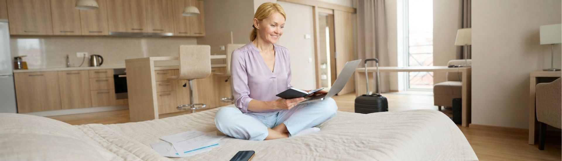 Mujer sonriente organizando su viaje médico en una habitación de hotel con su laptop, preparándose para una cirugía ocular en la Clínica Láser de Ojos Medellín.